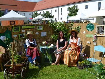 Die Steingadener Bluetentage Drei Damen sitzen in einer Gartenlaube der Steingadener Blütentage.