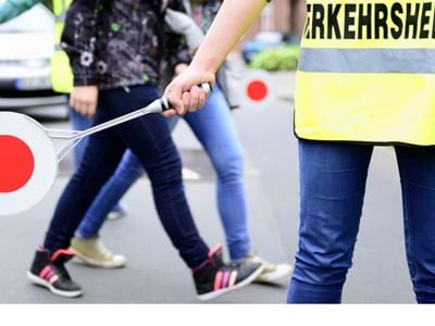 Verkehrshelfer Schüler die über die Straße gehen mit einem Verkehrshelfer