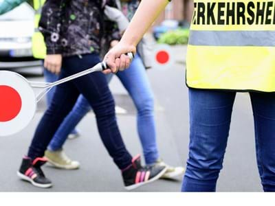 Schüler die über die Straße gehen mit einem Verkehrshelfer