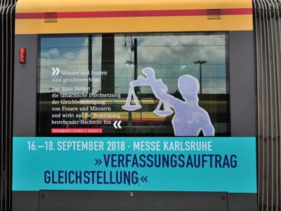 Zug mit Männchen und einer Waage Verfassungsauftrag Gleichstellung - Zug mit Männchen und einer Waage