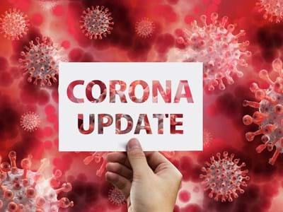 Corona-Update Zettel mit der Aufschrift Corona Update in einer Hand.