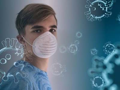 junger Mann mit FFP-Maske umgeben von Corona-Viren