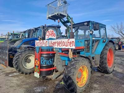 Blauer Traktor mit Aufschrift Das Faß ist übergelaufen